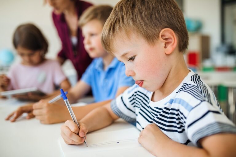 a-group-of-small-school-kids-with-teacher-in-class-writing.jpg